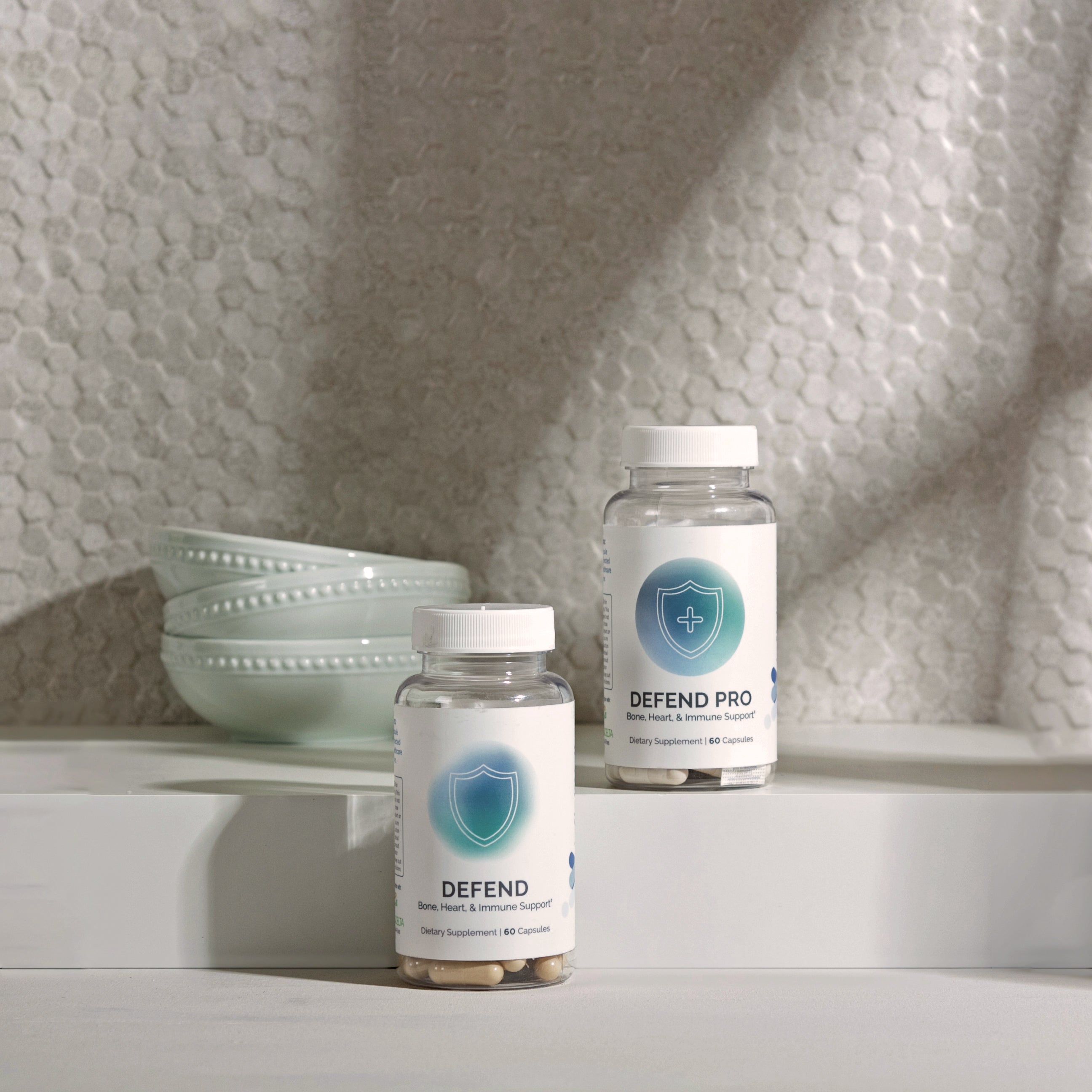 Two dietary supplement bottles, showcasing bone, heart, and immune support benefits, displayed on a kitchen counter.