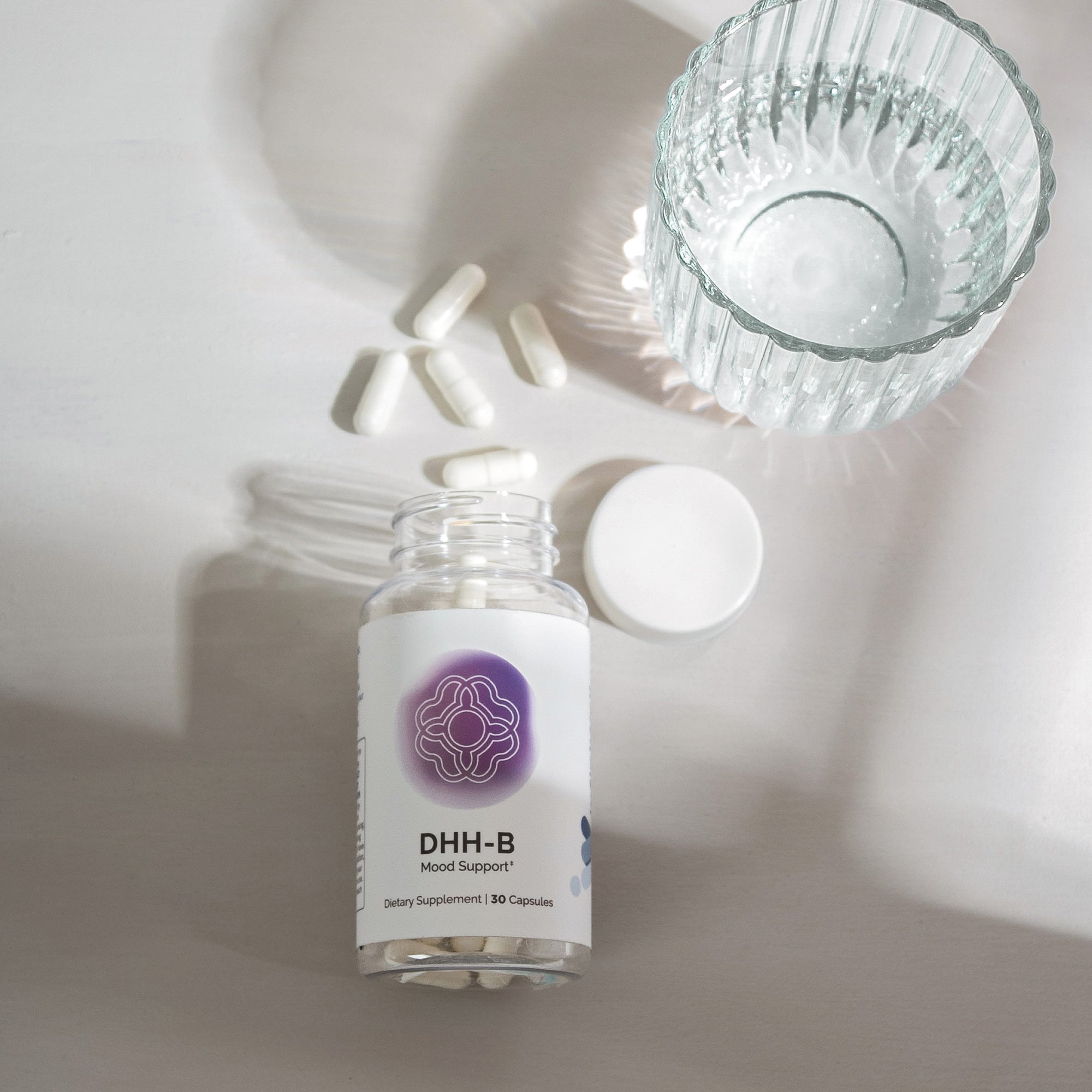 Mood support supplement bottle with capsules, alongside a glass of water.