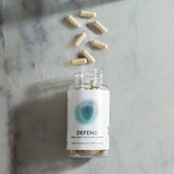 Beige capsules spilled from a clear bottle on a marble surface; 60 capsules total, supporting bone, heart & immune health.