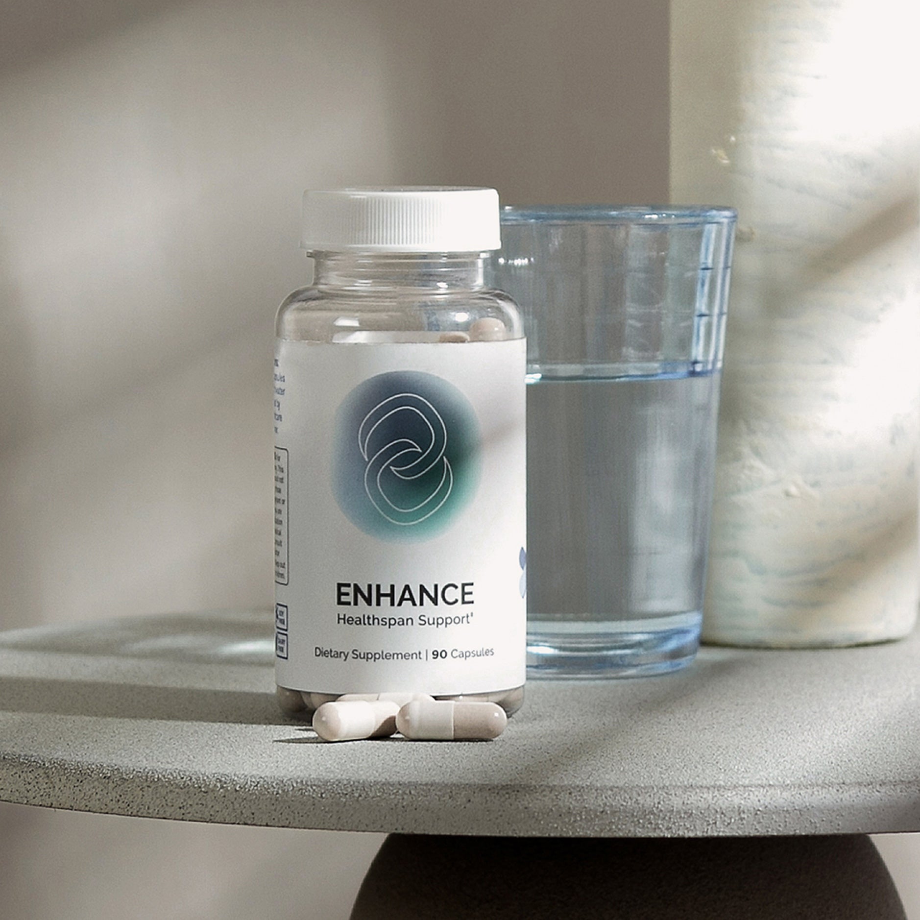 Healthspan supplement bottle with capsules, alongside a glass of water on a table.