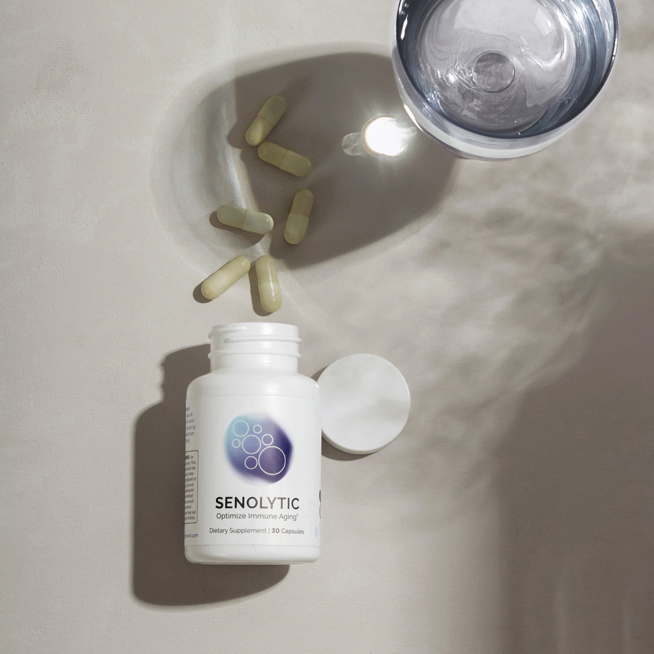 Dietary supplement bottle and pills, alongside a glass of water, on a neutral background.