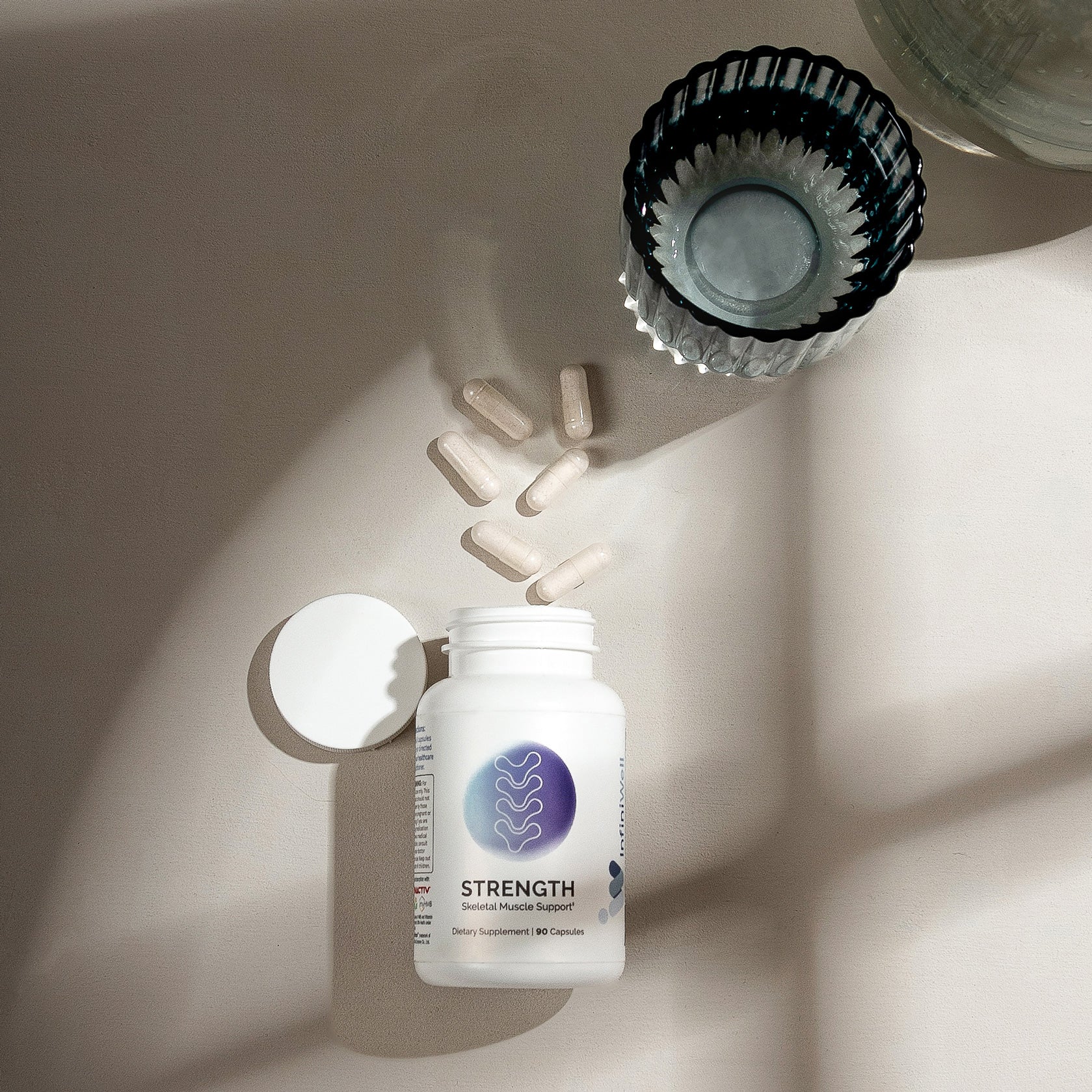 Beige background showing bottle of muscle support capsules; some spilled nearby.