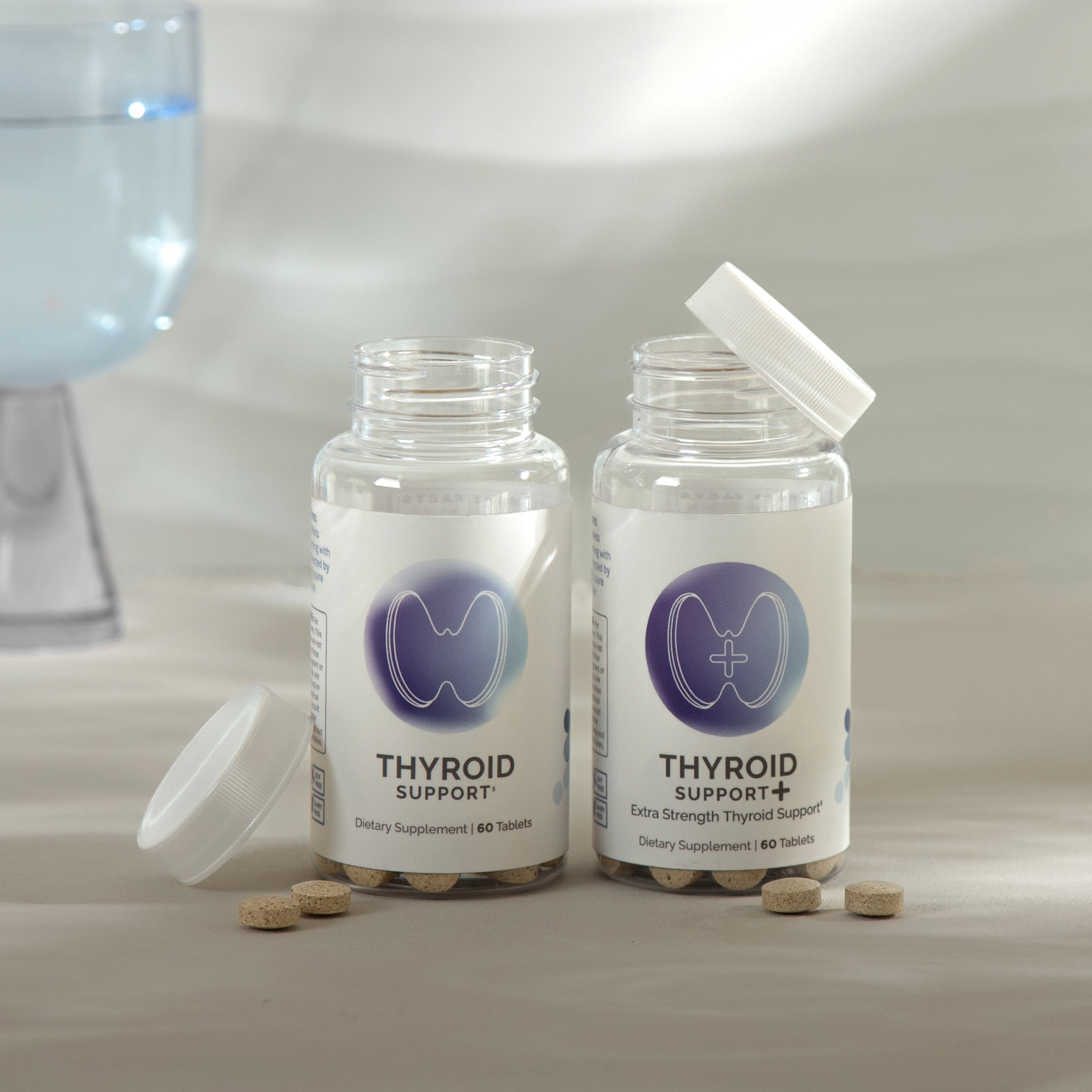 Two bottles of dietary supplements for thyroid health; one standard, one extra-strength; light beige tablets shown.
