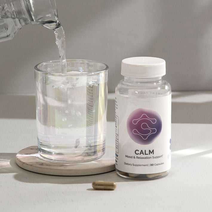 Mood & relaxation supplement bottle with 30 capsules, next to a glass of water.
