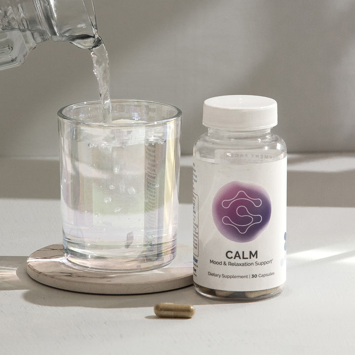 Mood & relaxation supplement bottle with 30 capsules, next to a glass of water.
