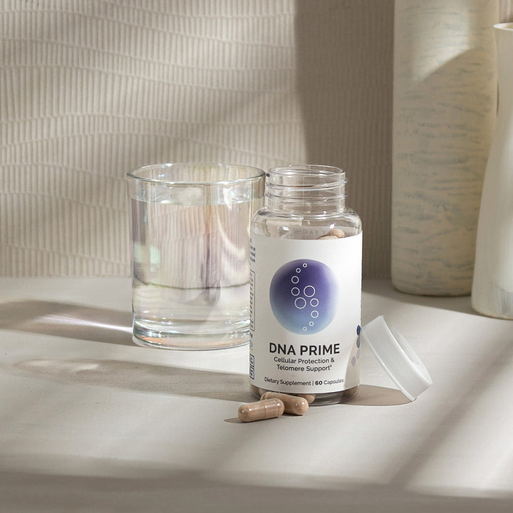 Dietary supplement bottle with capsules, next to a glass of water, on a light-colored surface.
