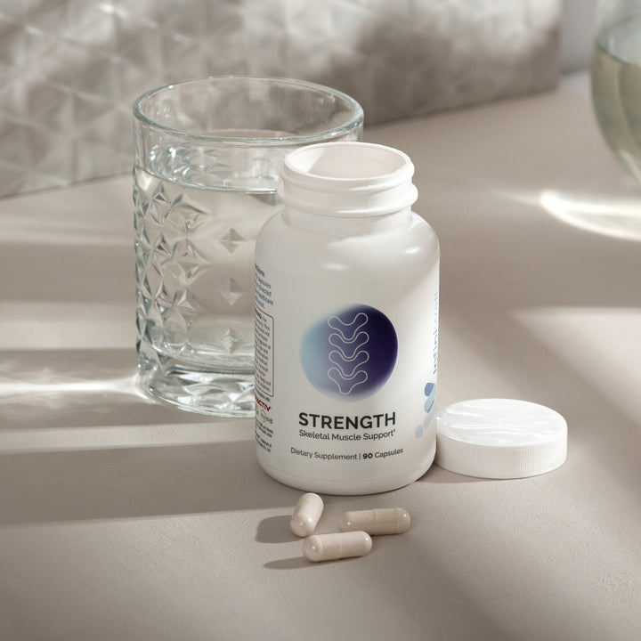 Skeletal muscle support supplement bottle, 90 capsules, with pills and water glass.

