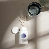 Beige background showing bottle of muscle support capsules; some spilled nearby.
