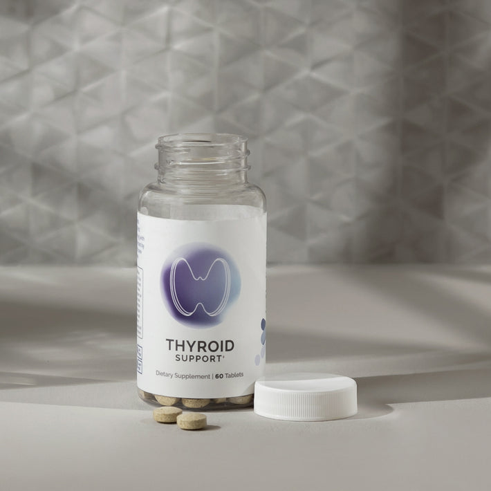 Infiniwell Thyroid Support supplement bottle with 60 tablets, open cap and tablets on light textured surface