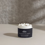 Open jar of InfiniWell Akkermansia-BPC Complex supplement filled with white capsules on a neutral tabletop.